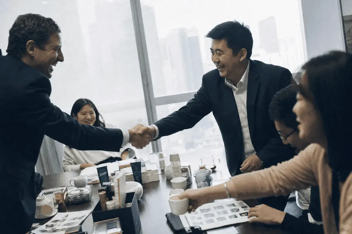 Brand manager shaking hands with a distribution executive in a Shanghai meeting room