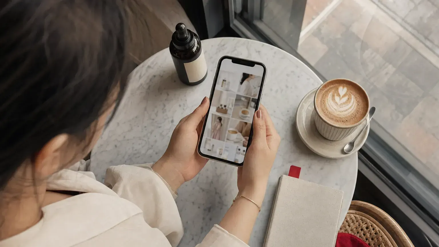 A shopper scrolls a feed of lifestyle photos on a phone at a cafe table in Shanghai